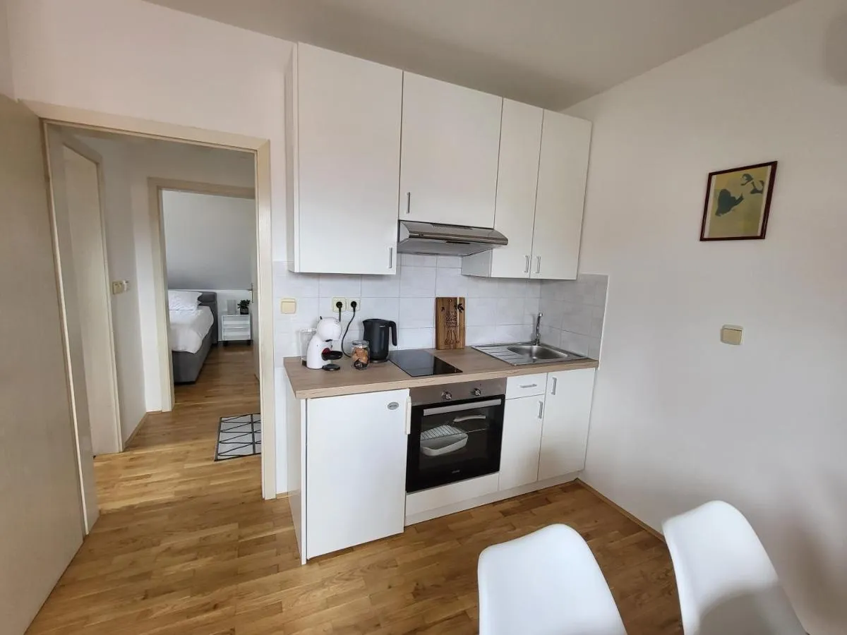 Bela kuhinja s pečico in pogled v spalnico