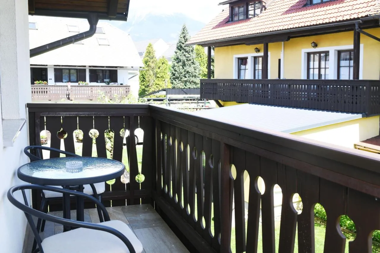 Balkon z rezljano leseno ograjo, mizico in stoli