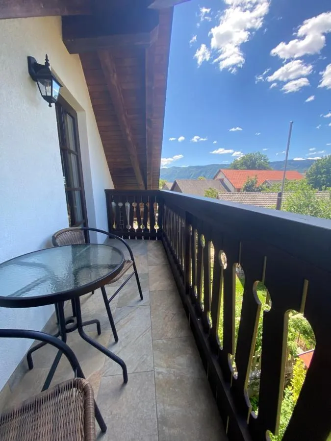 Balkon z mizico in stoli, pogled čez strehe vasi proti goram